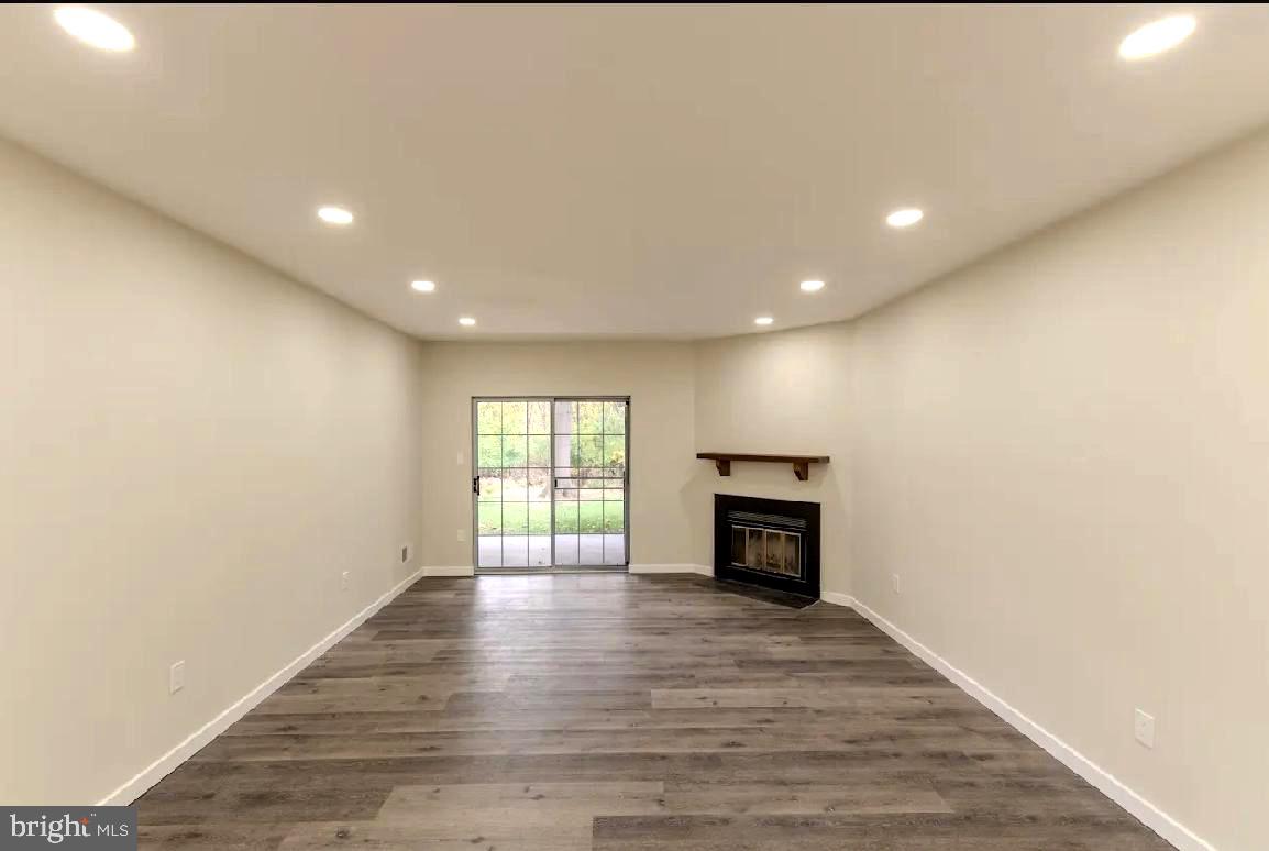 293 Valley Stream Lane, Unit 293 Chesterbrook, PA 19087 - Photo 6 of 18 an empty room with wooden floor fireplace and windows