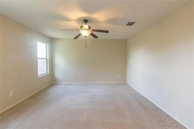 an empty room with windows and fan