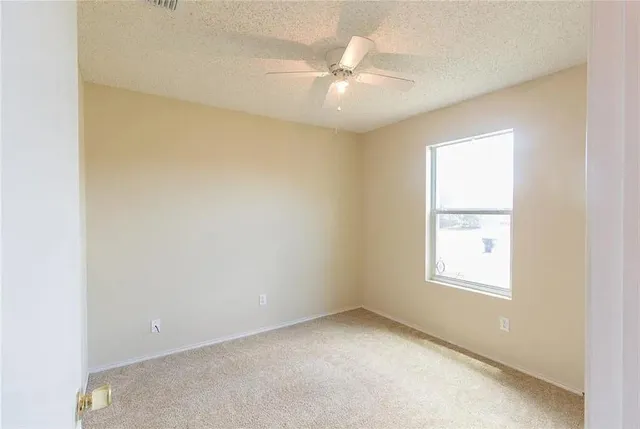an empty room with windows and fan