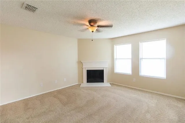 an empty room with windows and fan