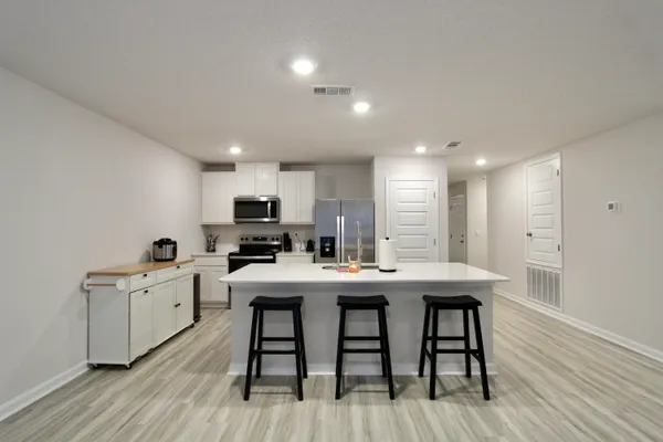 a view of a dining room with furniture a kitchen and chandelier