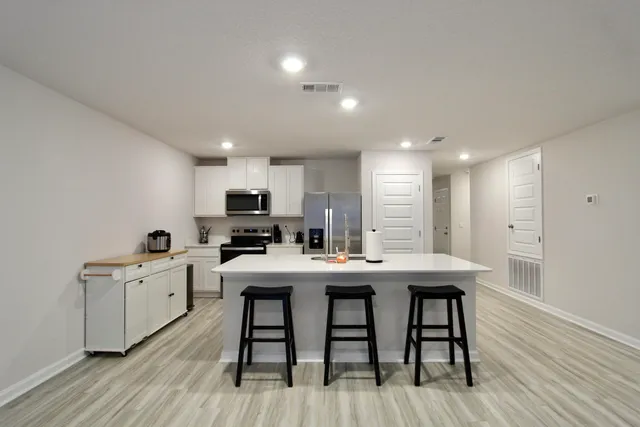 a view of a dining room with furniture a kitchen and chandelier