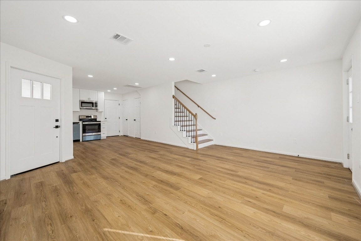 9913 Porto Rico Road Houston, TX 77041 - Photo 12 of 34 an empty room with wooden floor and kitchen view