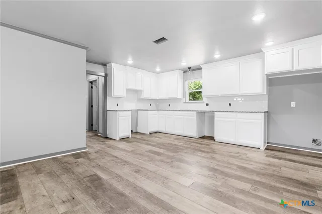 a view of a kitchen with white cabinets and stainless steel appliances