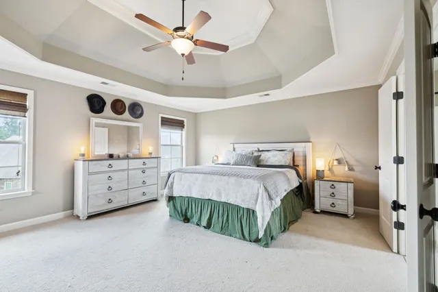 a spacious bedroom with a bed a dresser and a chandelier