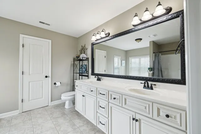 a bathroom with double vanity sink a mirror and a bathtub