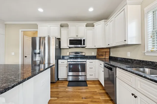a kitchen with granite countertop a refrigerator and a stove top oven