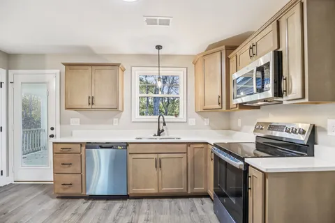 a kitchen with stainless steel appliances granite countertop a sink stove and cabinets