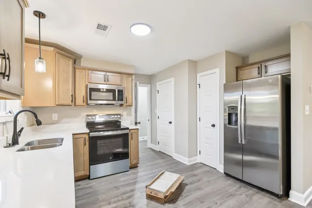 a kitchen with stainless steel appliances granite countertop a refrigerator a stove a sink and a microwave