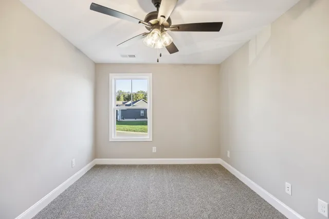 an empty room with a window and a ceiling fan