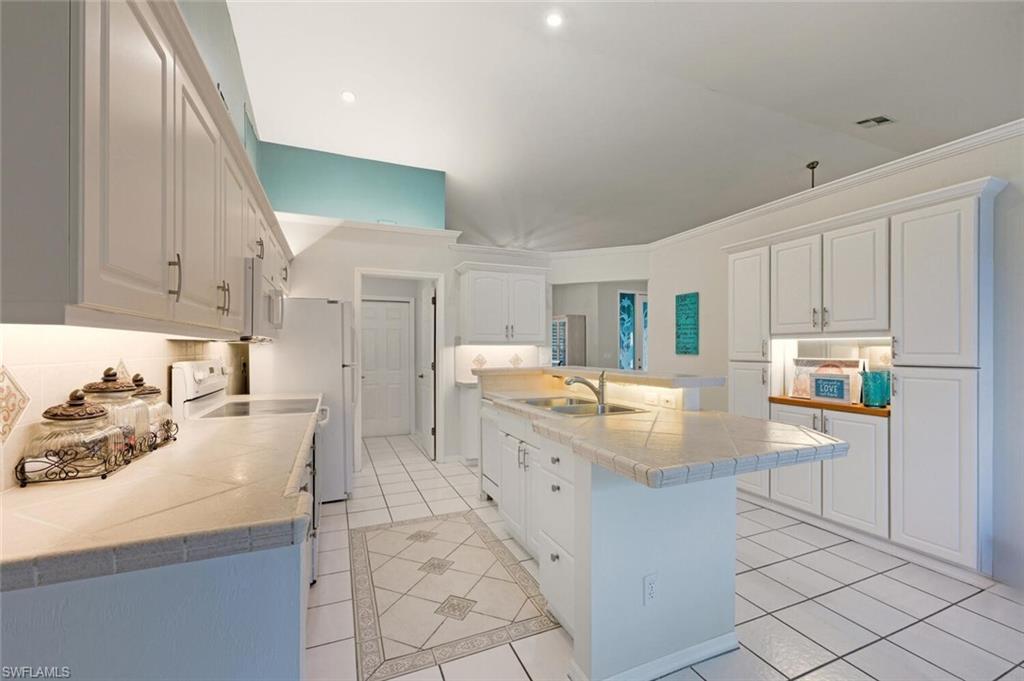 157 Versailles Circle Naples, FL 34112 - Photo 11 of 36 a kitchen with granite countertop cabinets and window