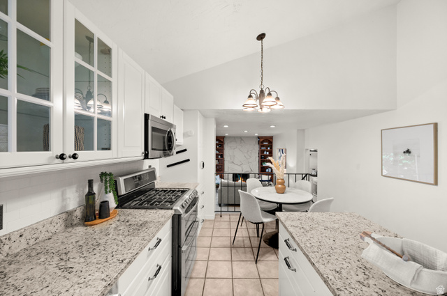 2163 Borg Drive Sandy, UT 84092 - Photo 8 of 31 Kitchen featuring stainless steel appliances, light stone countertops, white cabinets, glass insert cabinets, and vaulted ceiling