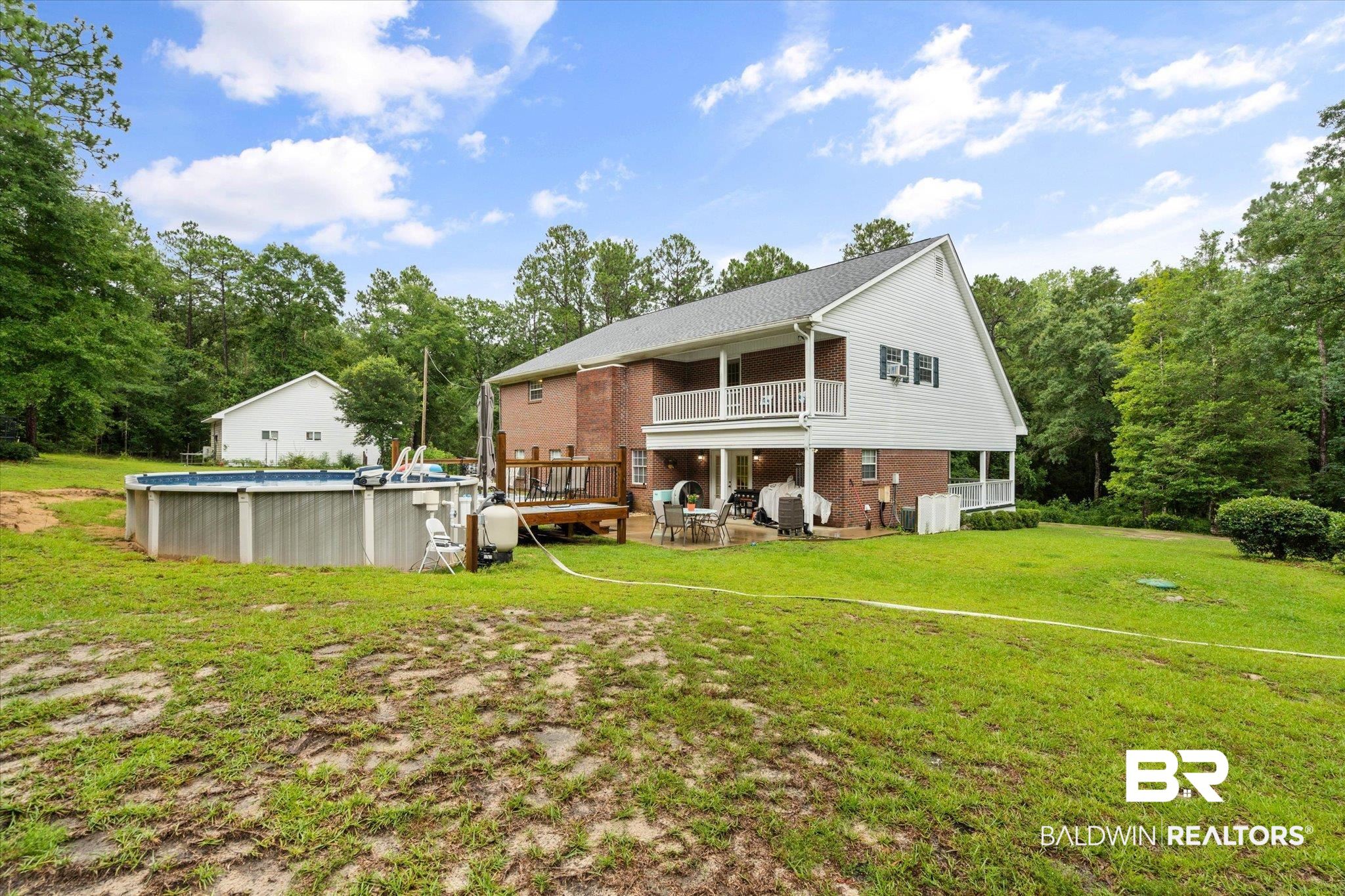 2300 Radcliff Road Saraland, AL 36571 - Photo 35 of 56 Rear view of property featuring brick siding, an outdoor pool, a lawn, and a balcony