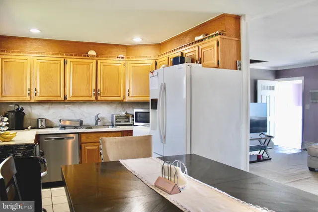 a kitchen with stainless steel appliances granite countertop a refrigerator a sink dishwasher a stove with wooden cabinets and floor