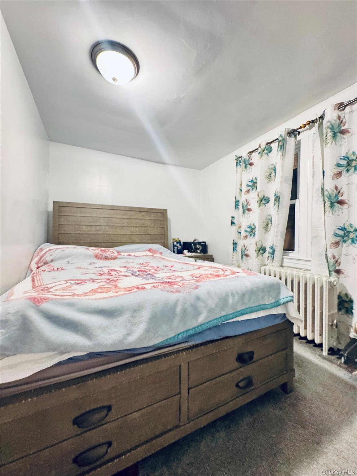 86-29 90th Street Queens, NY 11421 - Photo 12 of 14 Bedroom with radiator heating unit and dark colored carpet