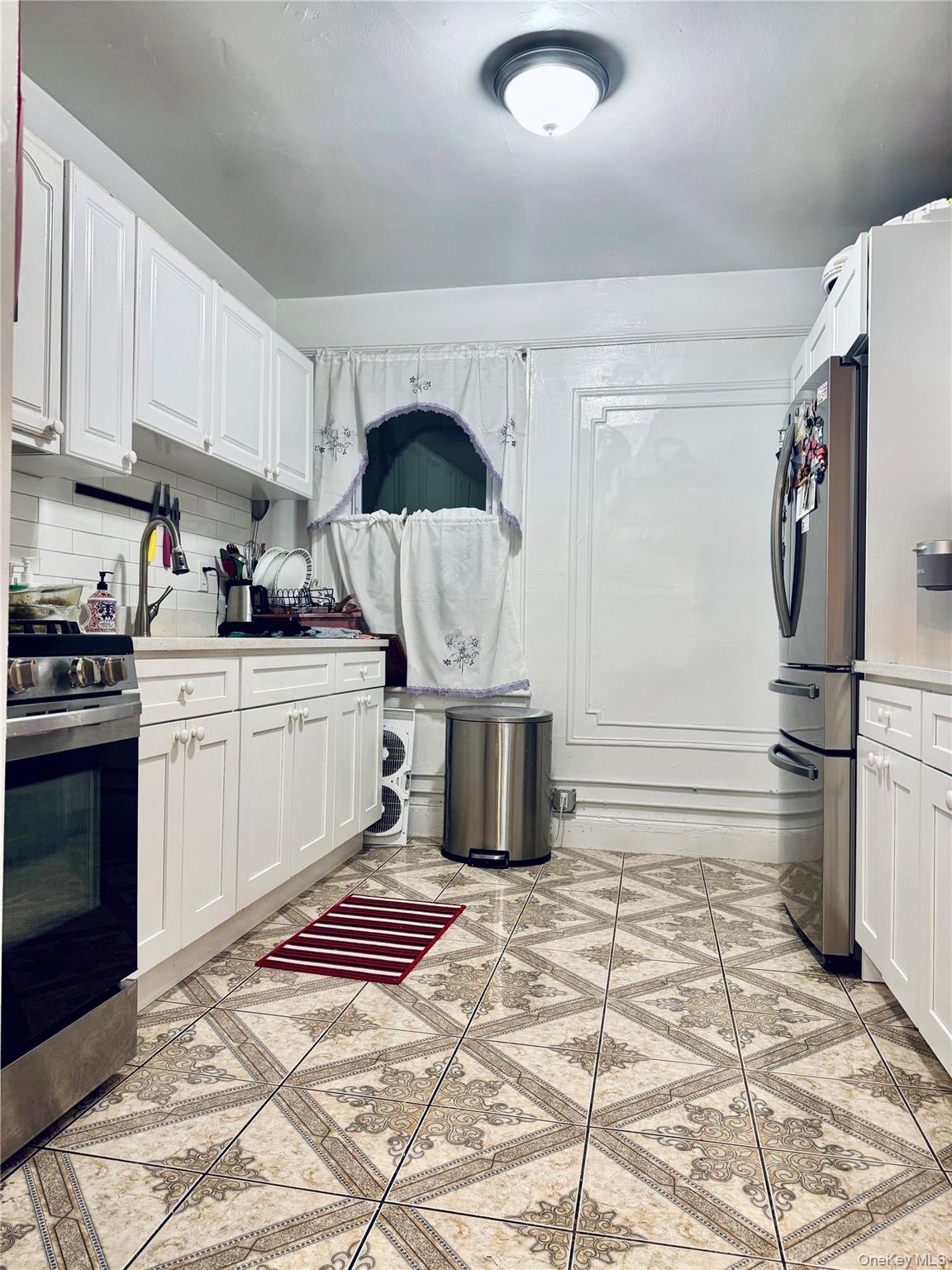 86-29 90th Street Queens, NY 11421 - Photo 4 of 14 Kitchen featuring appliances with stainless steel finishes, white cabinetry, and backsplash