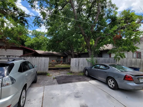 a backyard of a house with wooden fence and large trees