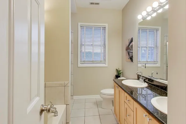 a bathroom with a granite countertop sink toilet and mirror
