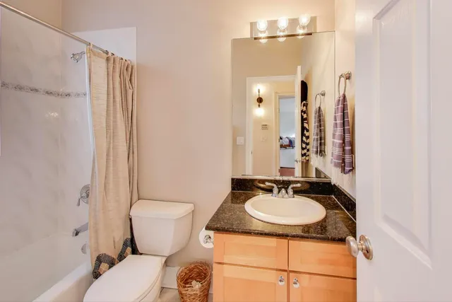 a bathroom with a granite countertop sink toilet a mirror and shower