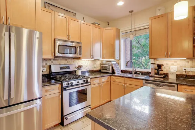 a kitchen with a refrigerator a stove a sink a window and cabinets