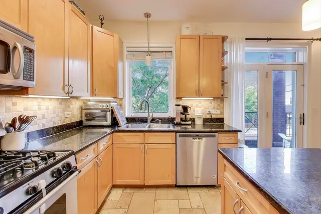 a kitchen with stainless steel appliances granite countertop a stove a sink and a microwave