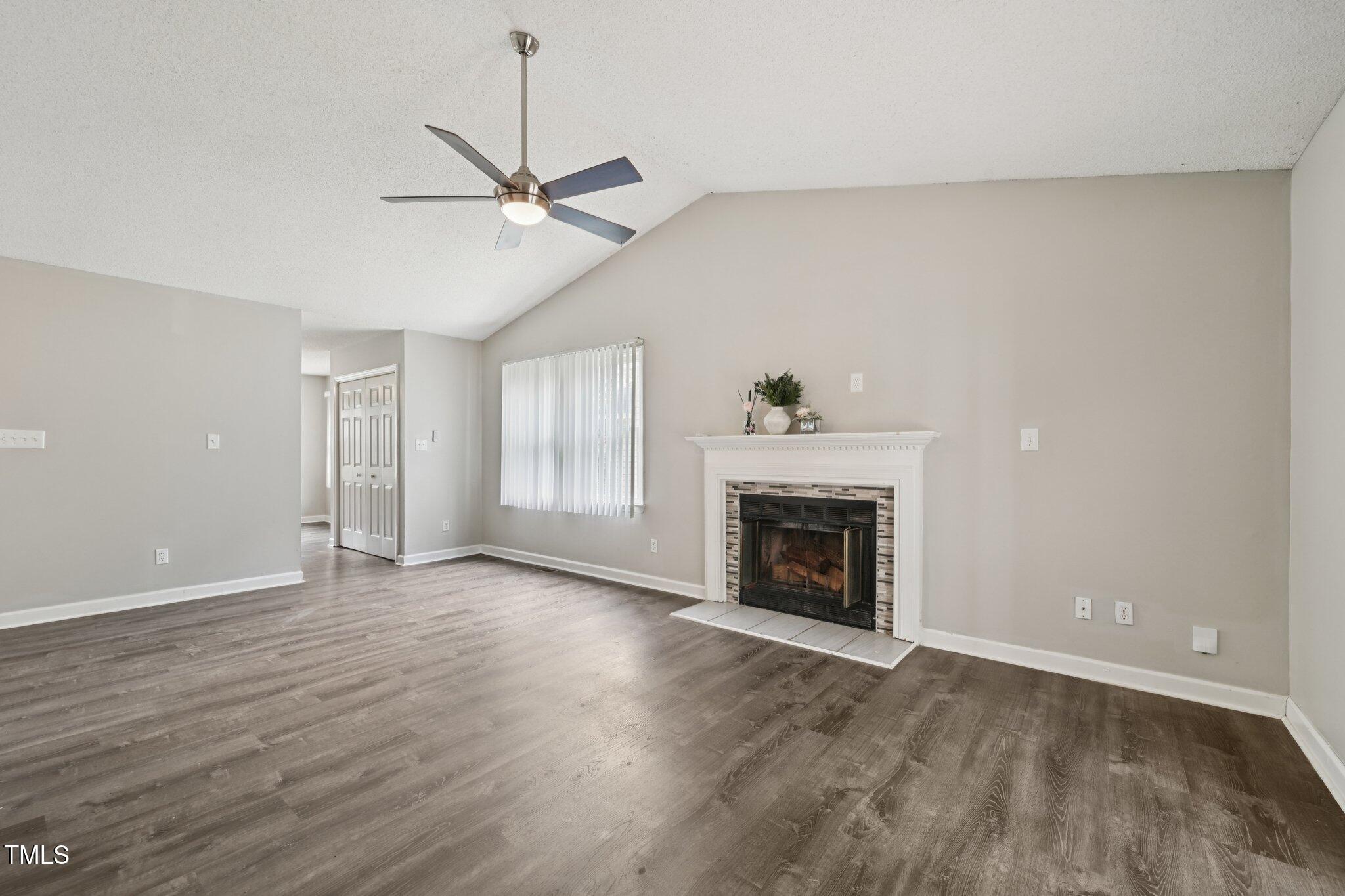 3534 Rawdon Drive Durham, NC 27713 - Photo 22 of 43 an empty room with wooden floor a ceiling fan a fireplace and windows