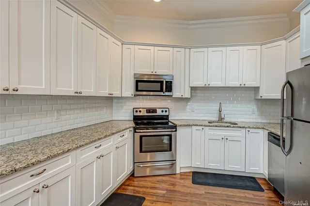a kitchen with granite countertop white cabinets and stainless steel appliances