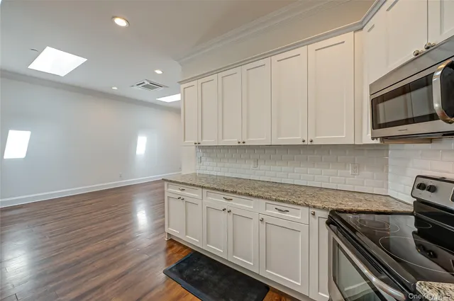a kitchen with granite countertop white cabinets and stainless steel appliances