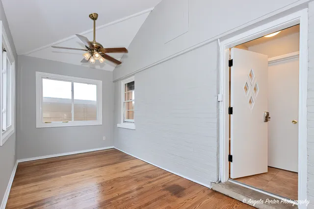 a view of empty room with wooden floor and fan