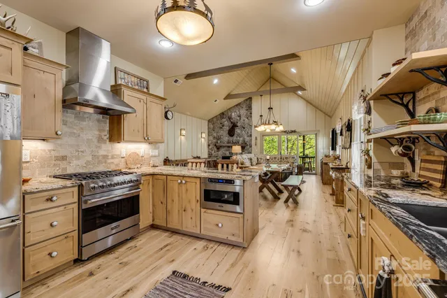 a kitchen with stainless steel appliances a stove a sink dishwasher a refrigerator oven and white cabinets with wooden floor