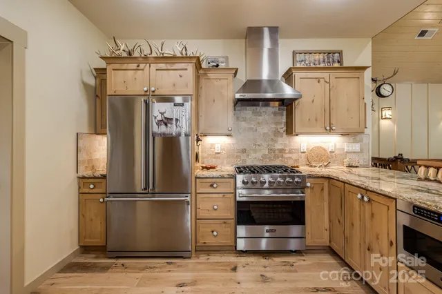 a kitchen with stainless steel appliances granite countertop a refrigerator a stove and a sink