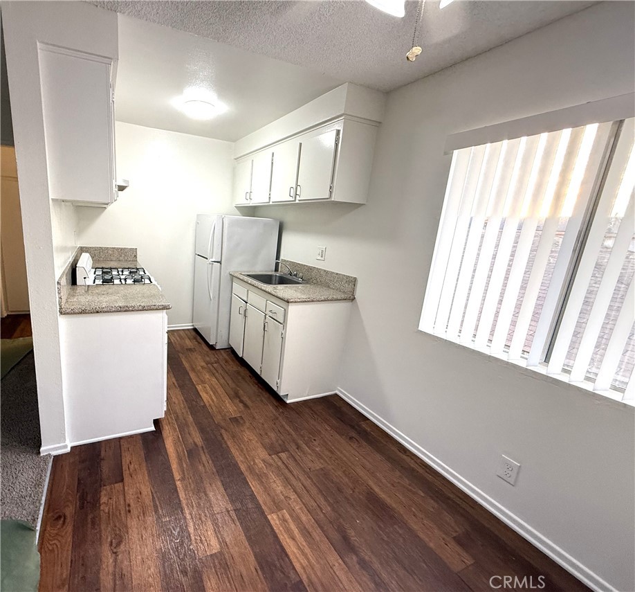 4015 137th Street, Unit 220 Hawthorne, CA 90250 - Photo 13 of 20 a kitchen with a hard wood floor white stove and white cabinets