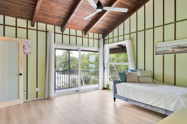 a living room with a bed and a large window with wooden floor