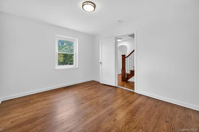 an empty room with wooden floor and a window