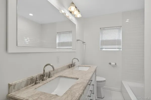 a bathroom with a granite countertop sink a toilet and a mirror
