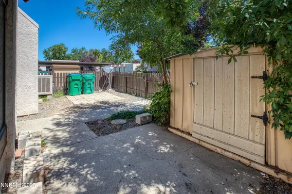 a view of a backyard with large tree and wooden fence