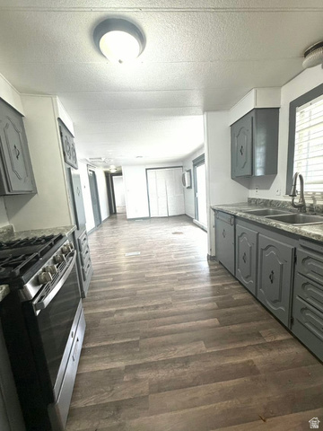 2491 Highway 89, Unit 114 Pleasant View, UT 84404 - Photo 18 of 18 Kitchen featuring gray cabinetry, stainless steel gas range, a textured ceiling, open floor plan, and dark wood-type flooring