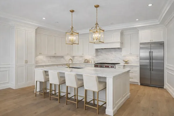 a kitchen with stainless steel appliances kitchen island granite countertop a stove a refrigerator and a chandelier
