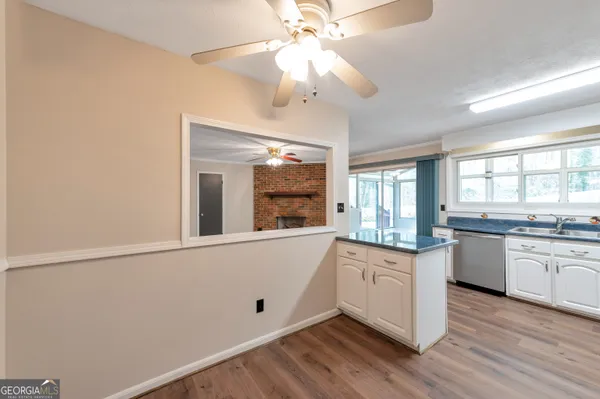 a large white kitchen with granite countertop a stove a sink and dishwasher with wooden floor