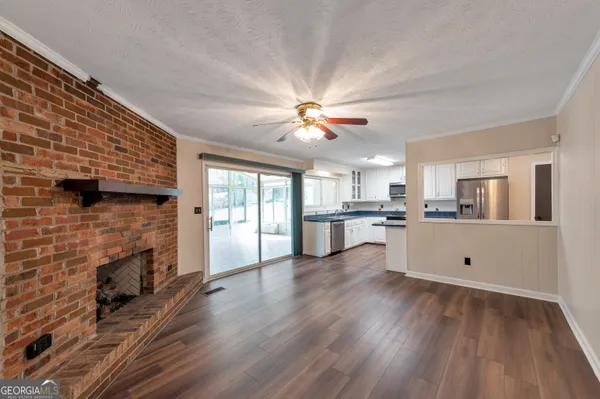 a view of open kitchen with granite countertop a stove top oven a chimney cabinets and wooden floor
