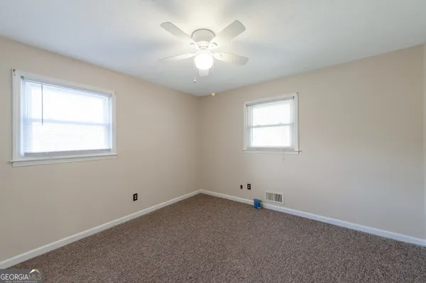 an empty room with a window and a fan