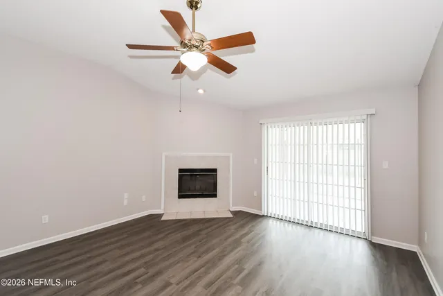 an empty room with wooden floor fan and windows