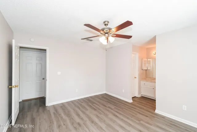 an empty room with wooden floor and a ceiling fan