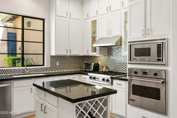 a kitchen with granite countertop a sink stove and cabinets
