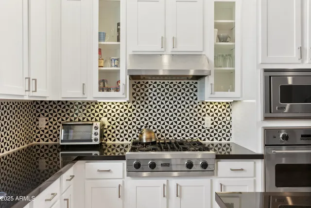 a kitchen with granite countertop white cabinets and black appliances