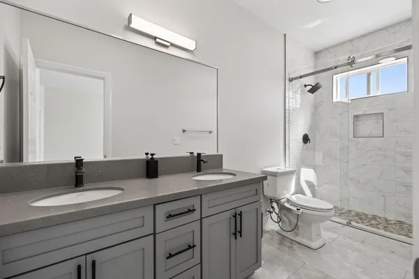 a bathroom with a double vanity sink toilet and shower