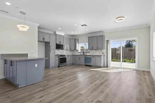 a large kitchen with stainless steel appliances granite countertop a stove a sink dishwasher and a refrigerator with wooden floor