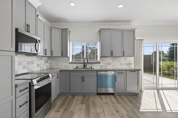 a kitchen with stainless steel appliances granite countertop a stove a sink and a microwave