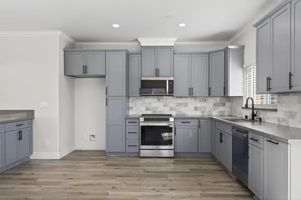 a kitchen with stainless steel appliances granite countertop a stove top oven a sink and a refrigerator