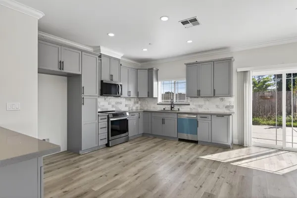a large kitchen with cabinets wooden floor and stainless steel appliances